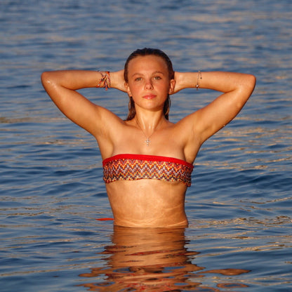 Bikini model in water wearing Red Sangria reversible bandeau bikini top by Bikini Flavors.  Cherry red reverses to colorful print.  American Made. 